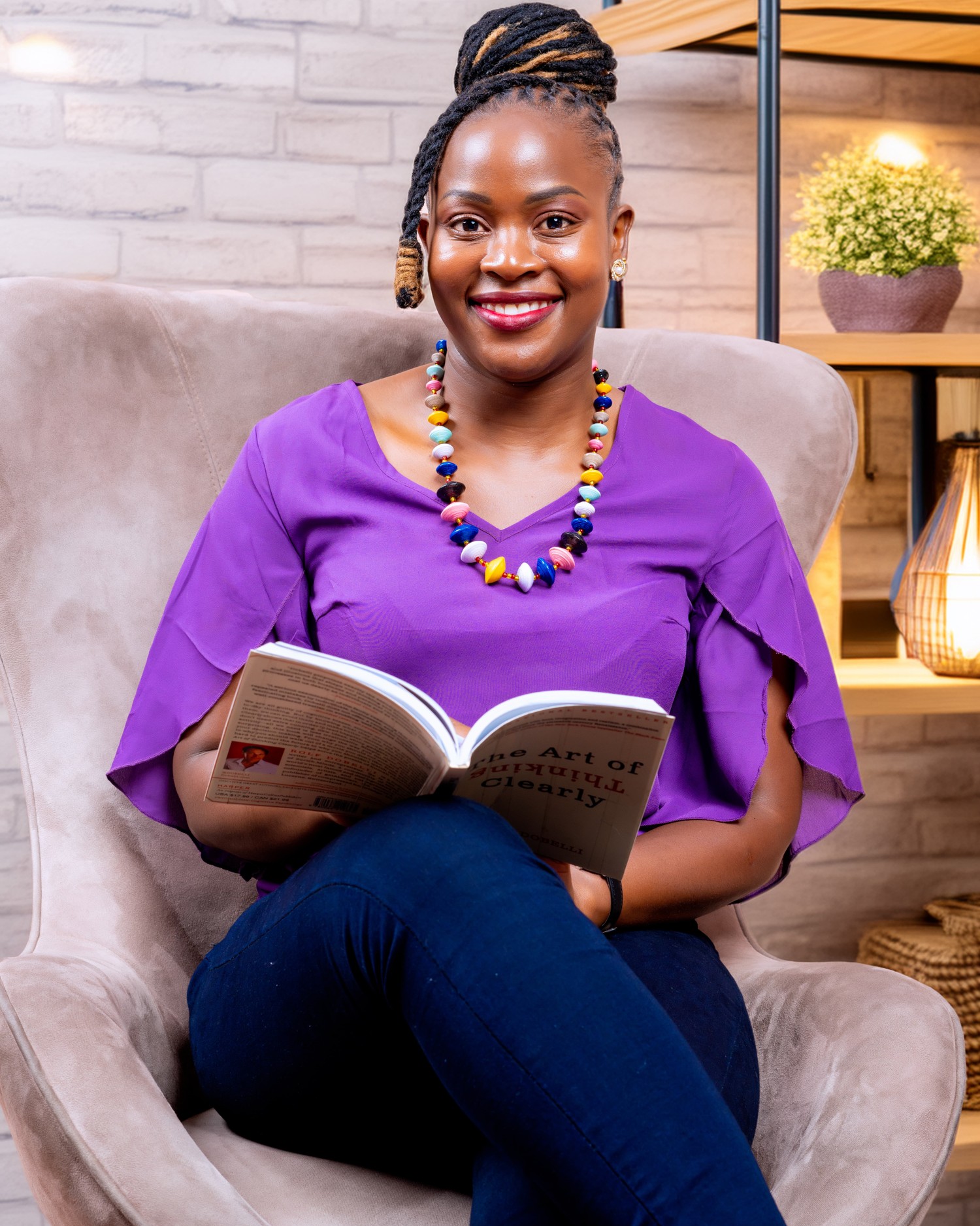 Getty Nasike sitting in an armchair, reading, wearing a purple top